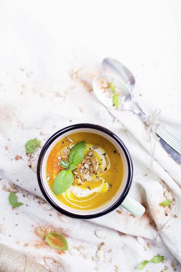 Pumpkin Soup In An Enamel Mug; Decorated With Fresh Basil And Sunflower Seeds Photograph by Natalia Mantur