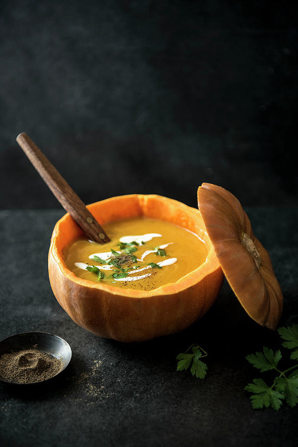 Pumpkin Soup Served In Pumpkin With Fresh Parsley, Cream And Pepper Photograph by Magdalena Hendey