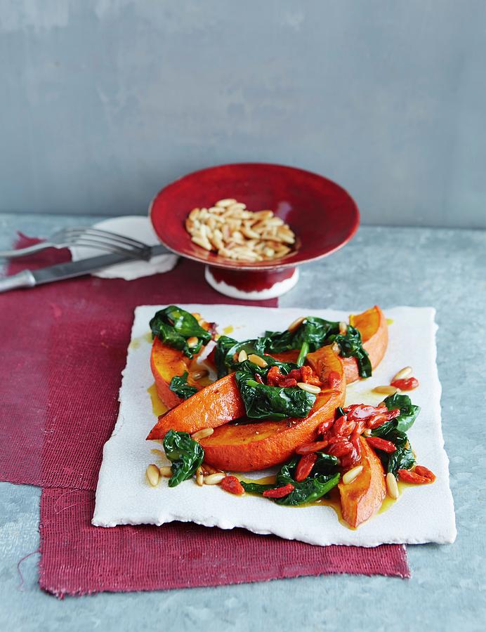 Pumpkin Wedges On Wilted Spinach With Goji Berries Photograph by Jalag / Julia Hoersch