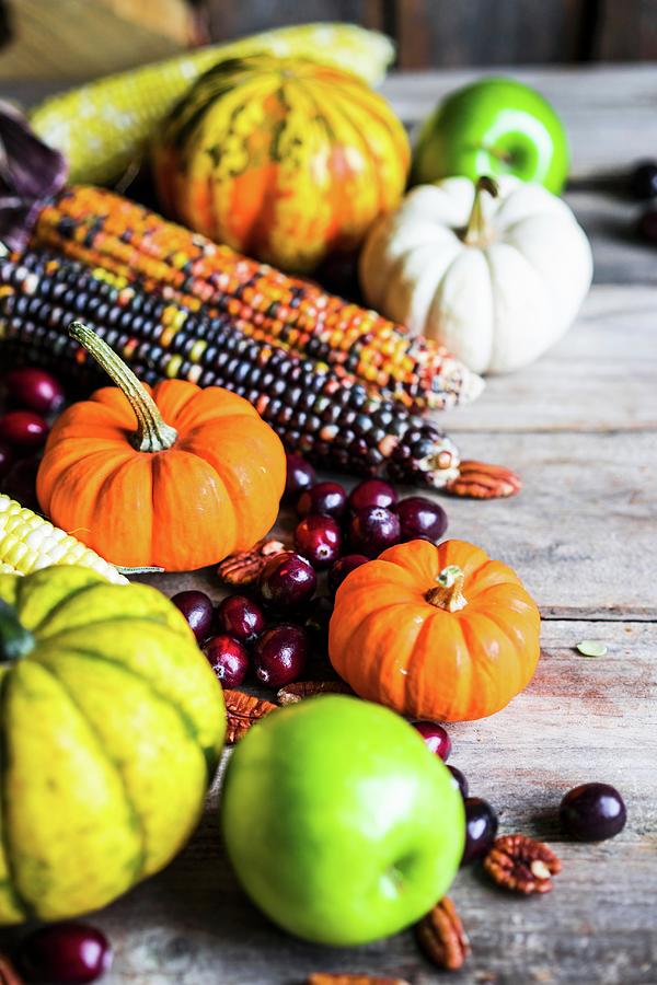 Pumpkins, Corn Cobs, Apples, Nuts And Cranberries On A Wooden Surface Photograph by Alena Haurylik