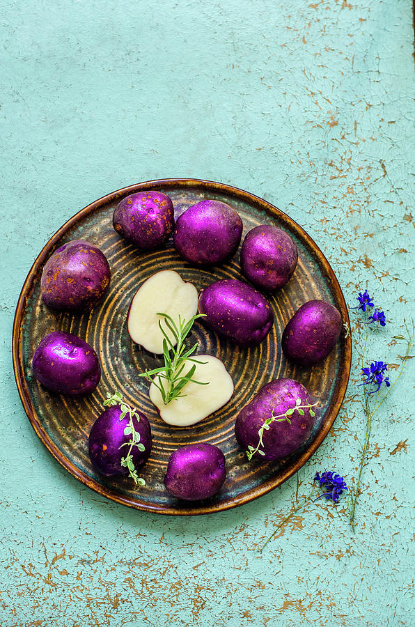 Purple Potatoes With Thyme And Rosemary On A Blue Old Table Photograph by Gorobina