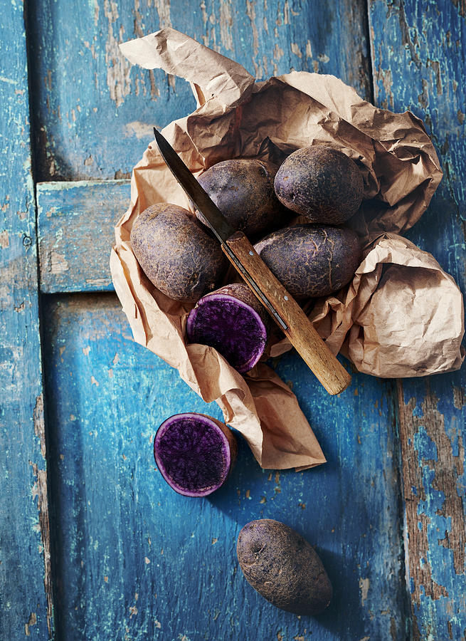 Purple Potatoes Wrapped In Paper With A Knife Photograph by Stefan Schulte-ladbeck