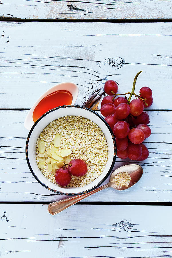 Quinoa Flakes, Honey, Almonds And Grapes For Healthy Breakfast On White Wooden Background Photograph by Yuliya Gontar