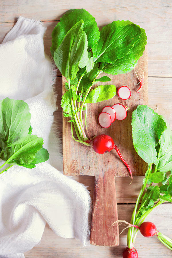 Radishes With Leaves On A Wooden Board, Whole And Sliced Photograph by Sabine Lscher