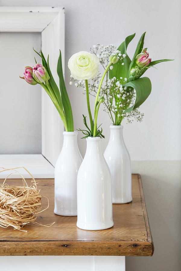 Ranunculus, Tulips And Gypsophila In Three White Bottles Photograph by Catja Vedder
