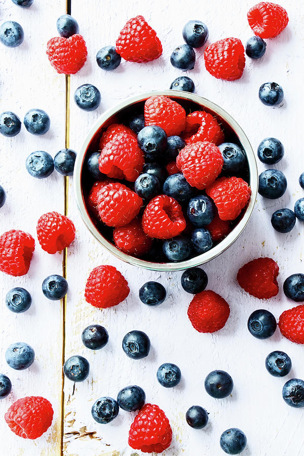 Raspberries And Blueberries In A Bowl Against A Wooden Background top View Photograph by Yuliya Gontar