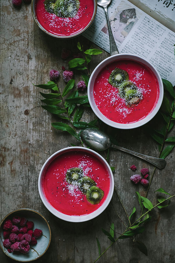 Raspberries Smoothies In Three Bowls On A Wooden Table With A Newspaper Photograph by Lucie Beck