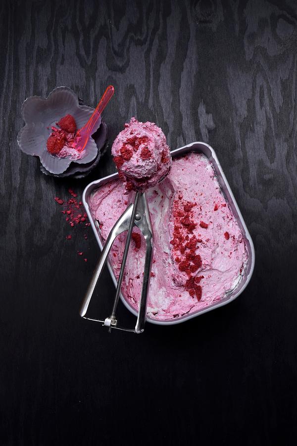 Raspberry And Yoghurt Ice Cream In An Ice Cream Container, An Ice Cream Scoop, And A Scoop Of Ice Cream Photograph by Elli Briest
