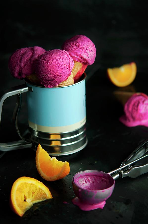 Raspberry Ice Cream In Cones With An Ice Cream Scoop And Orange Wedges Photograph by Kristy Snell