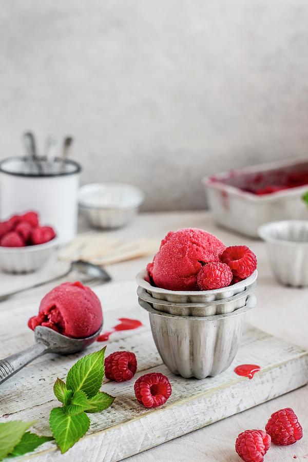 Raspberry Sorbet In Metal Bowls With An Ice Cream Scoop On A Wooden Board Photograph by Magdalena Hendey