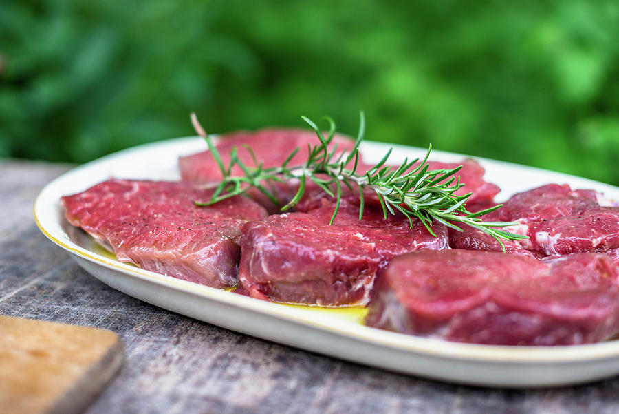 Raw Beef Loin Steaks With Rosemary In A Garden Kitchen Photograph by Sebastian Schollmeyer