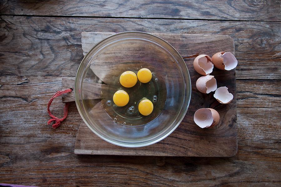 Raw Eggs In A Glass Bowl And Eggshells On A Wooden Board Photograph by Christophe Madamour