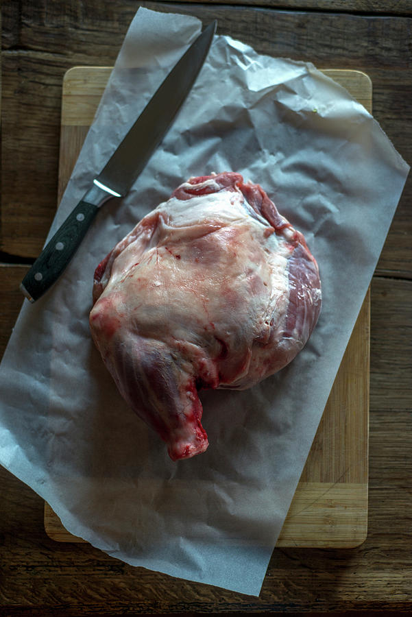 Raw Lamb Shoulder With A Knife On Parchment Paper Photograph by Roger Stowell