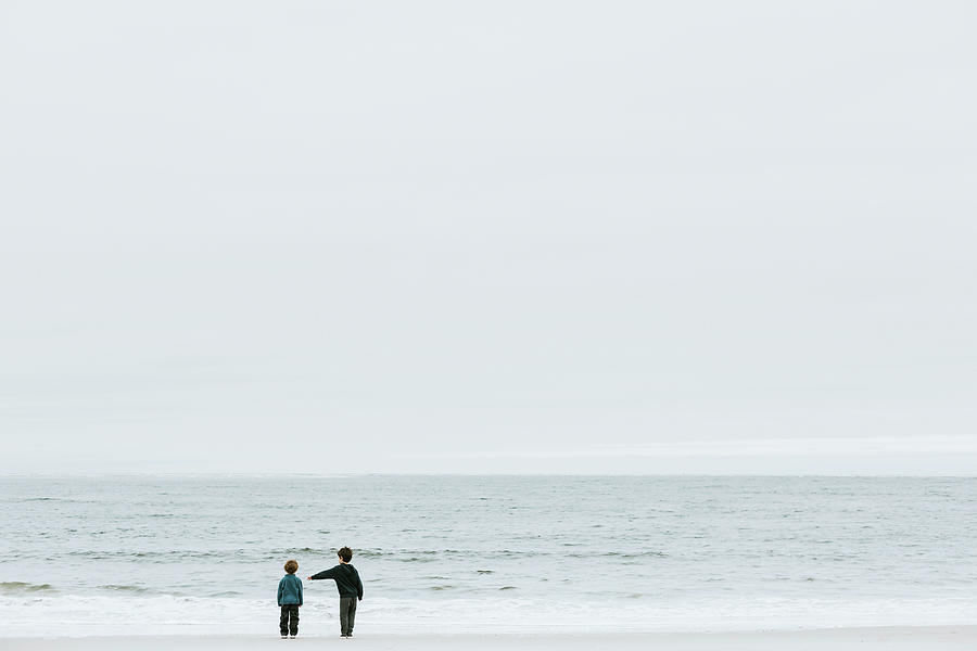 Nature Photograph - Rear View Of Brothers Standing At Beach Against Sky by Cavan Images