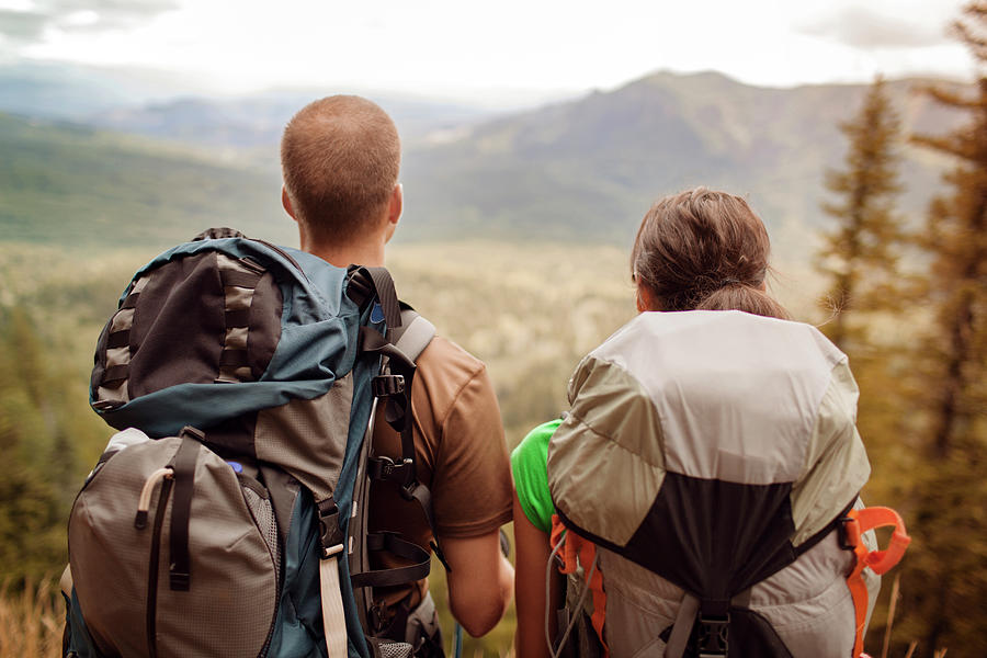 Rear View Of Couple Carrying Backpacks While Looking At Mountains ...