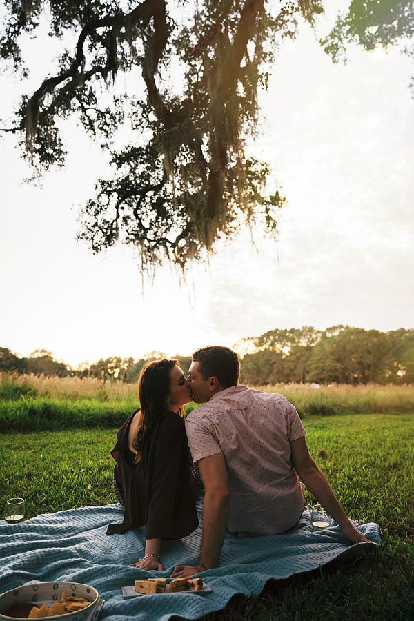 Rear View Of Couple Kissing While Relaxing On Blanket At Park During ...