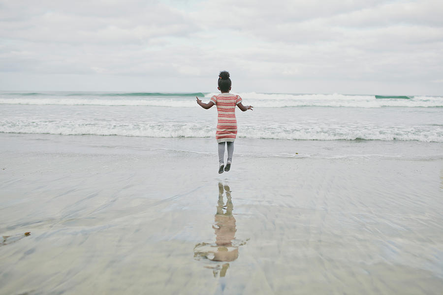 Rear View Of Girl Jumping At Beach Photograph by Cavan Images | Pixels