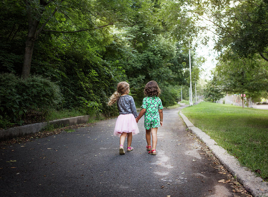 Rear View Of Girls Holding Hands While Walking In Park Photograph by ...