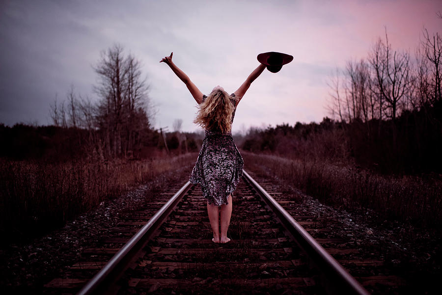 Nature Photograph - Rear View Of Happy Woman With Arms Raised Standing At Railroad Tracks Against Cloudy Sky by Cavan Images