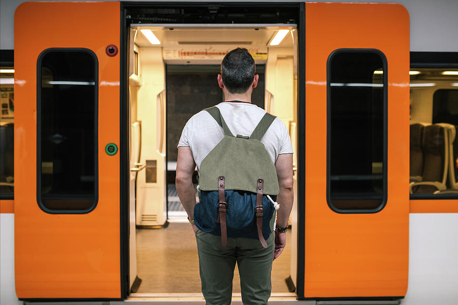 Rear View Of Man With Backpack Standing At Train Entrance On Railroad ...