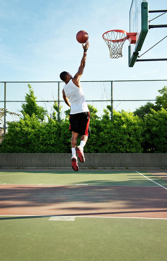 Basketball Photograph - Rear View Of Sportsman Dunking Ball In Hoop At Court by Cavan Images