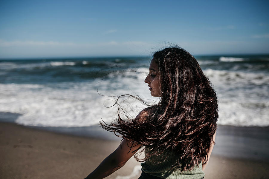 Rear View Of Teenage Girl Standing At Beach Against Blue Sky During ...