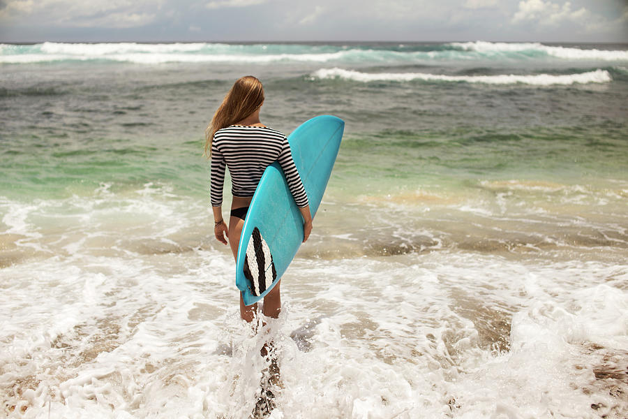 Rear View Of Woman Carrying Surfboard While Standing In Sea Photograph