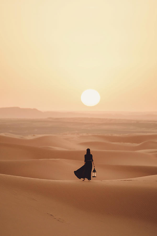 Sunset Photograph - Rear View Of Woman Holding Lantern While Standing At Sahara Desert Against Sky During Sunset by Cavan Images