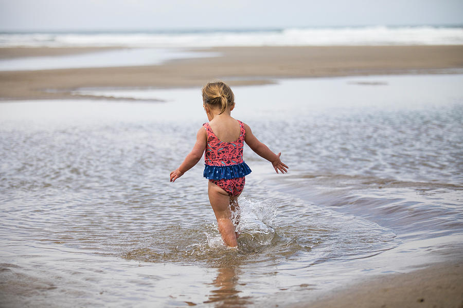 Rear View Of Young Girl Running Through Tidal Pool At The Beach ...