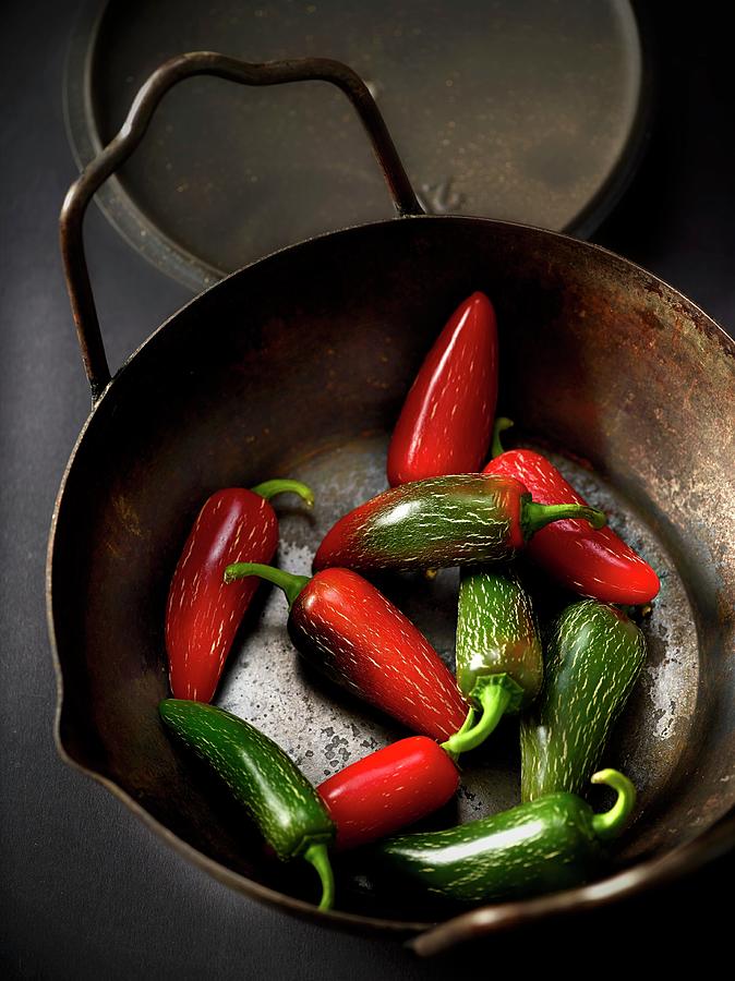 Red And Green Chilli Peppers In An Iron Pot Photograph by Frdric Perrin