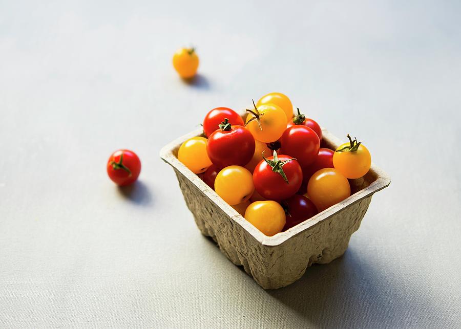 Red And Yellow Cherry Tomatoes In A Cardboard Container Photograph by Lisa Rees