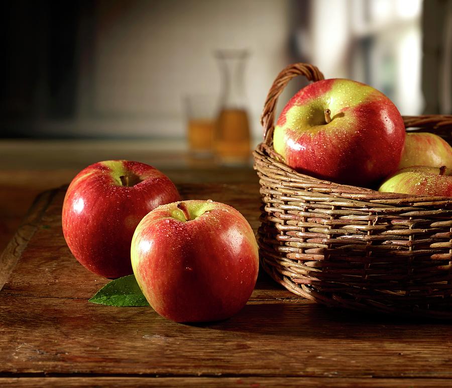 Red Apples On A Wooden Table And In Basket Photograph by Ludger Rose
