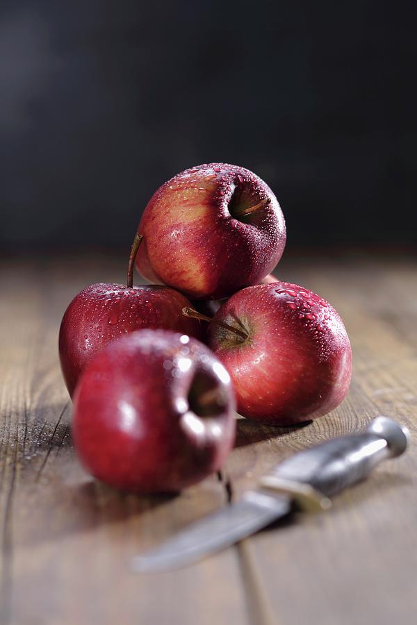 Red Apples With Droplets Of Water And A Knife, On A Wooden Surface Photograph by Frank Weymann