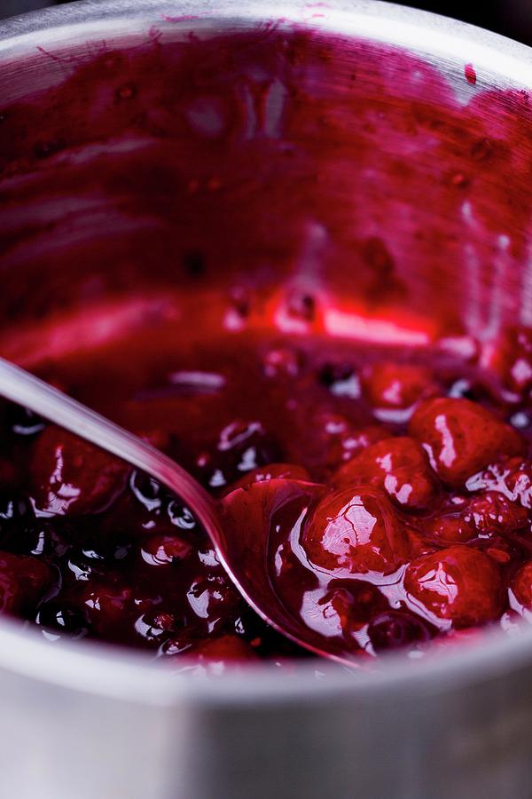 Red Berry Compote In Pan With Spoon Photograph by Claudia Timmann