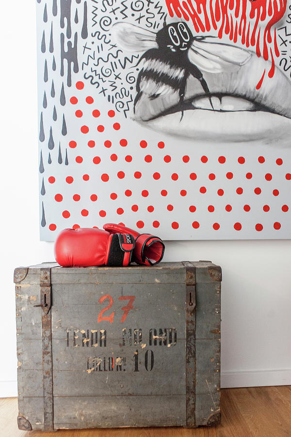 Red Boxing Gloves On Old Wooden Trunk In Front Of Modern Artwork Photograph by Anne-catherine Scoffoni