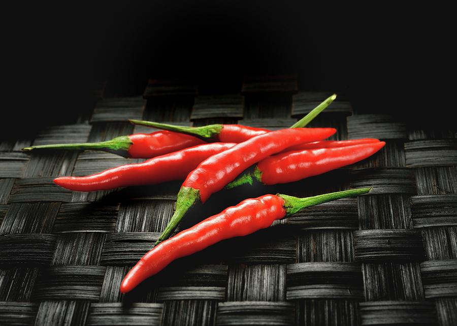 Red Chilli Peppers On A Black Woven Mat Photograph by Kaktusfactory
