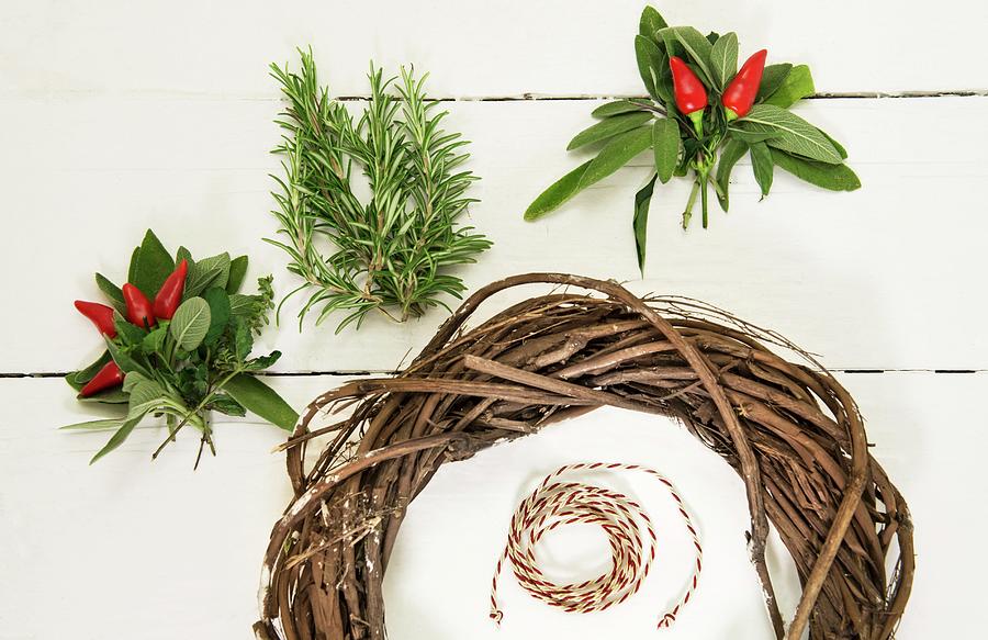 Red Chillies, Sage Leaves, Rosemary And Willow Wreath On White Surface Photograph by Vierucci/eustachi
