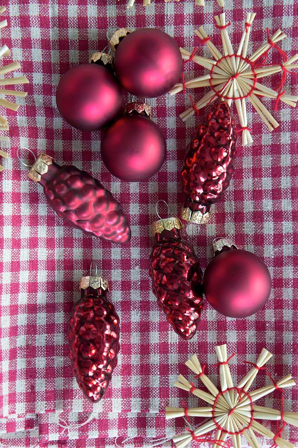 Red Christmas Tree Decorations And Straw Stars On Gingham Cloth Photograph by Martina Schindler