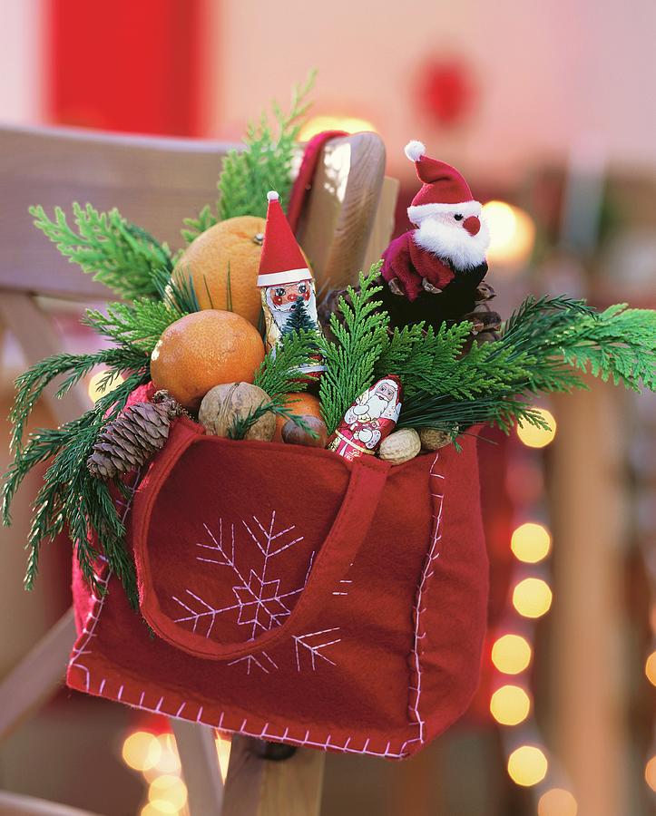 Red Felt Bag Filled With Father Christmases, Mandarins And Nuts Photograph by Strauss, Friedrich