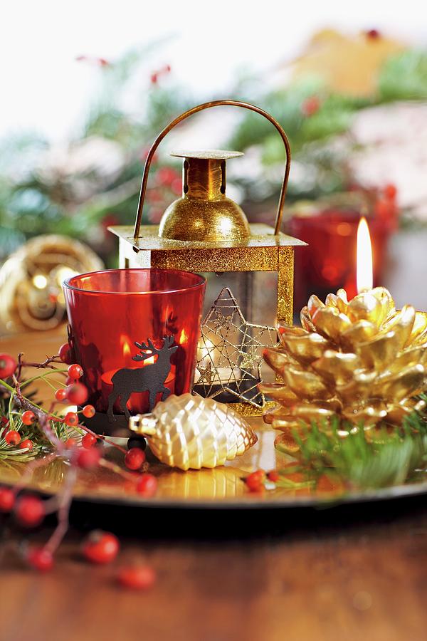 Red Glass Tealight Holder, Gilt Lantern And Pine Cone Decorations On Platter Photograph by Biglife