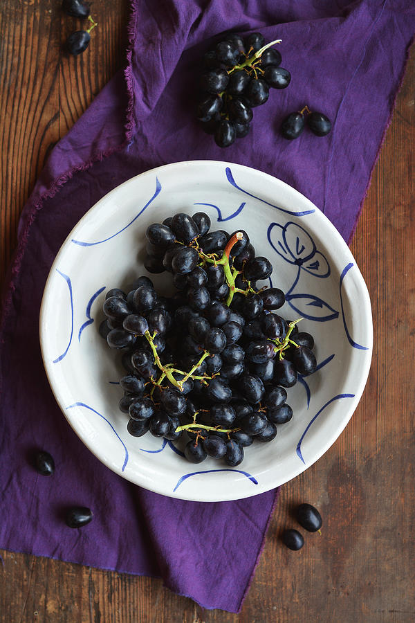 Red Grapes In A Rustic, Hand-painted Bowl On A Wooden Table Photograph by Mariola Streim