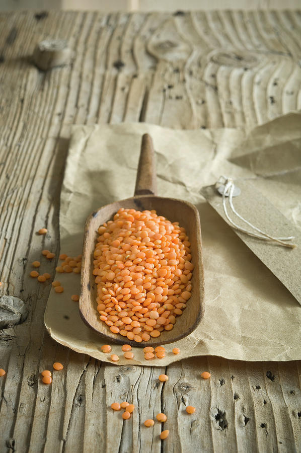 Red Lentils In Wooden Scoop Photograph by Achim Sass