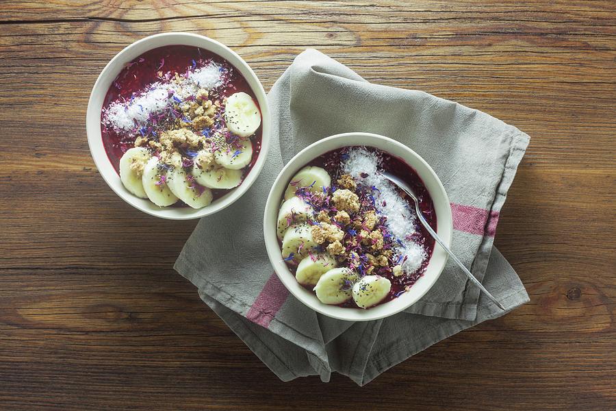 Red Smoothie Bowls With Chia Seeds And Edible Flowers On A Wooden Table Photograph by Barbara Pheby