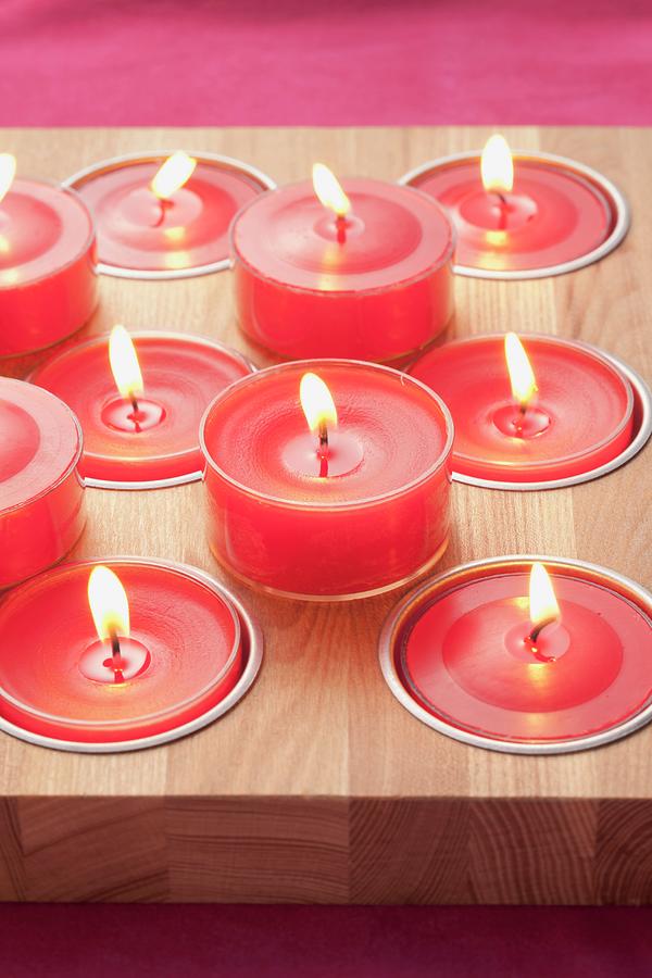 Red Tealights On And In Wooden Board Photograph by Foodcollection
