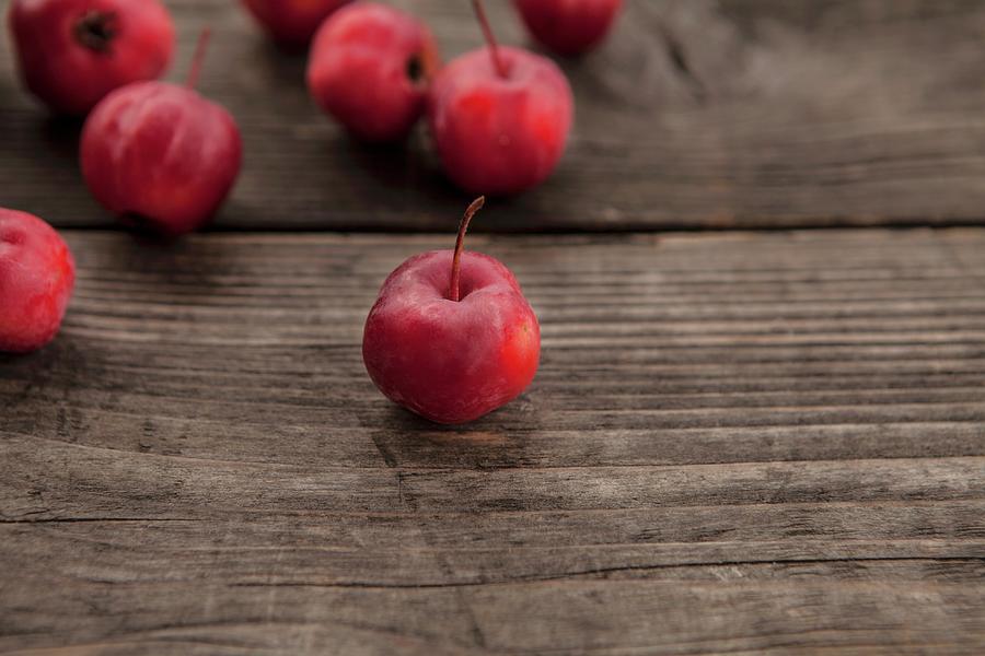 Red Wild Apples On A Wooden Surface Photograph by Nika Moskalenko