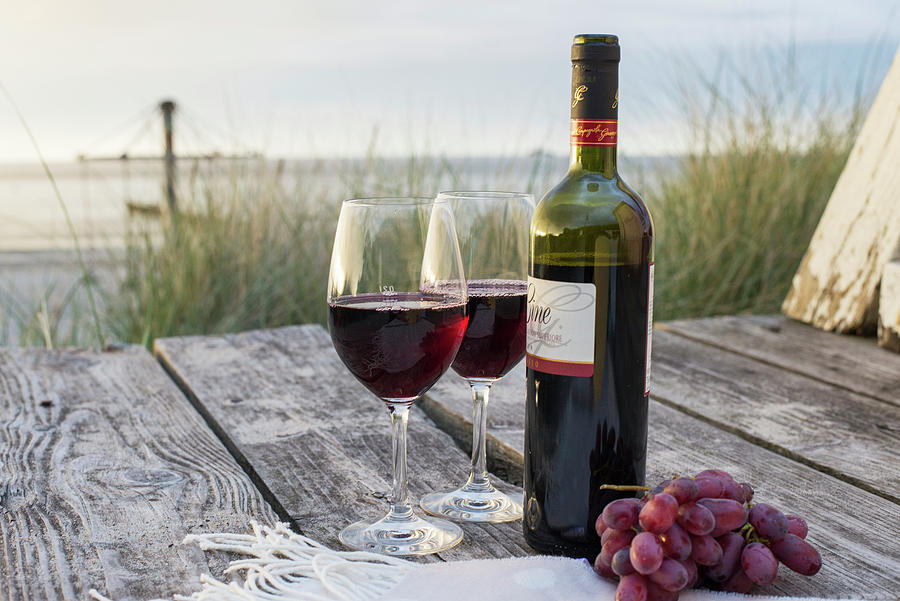 Red Wine And Grapes On A Wooden Table On A Beach Photograph by Jelena Filipinski