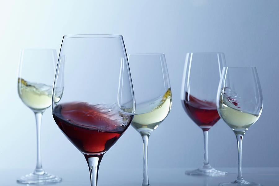 Red Wine And White Wine Swirling In Glasses Photograph by Jalag / Gtz Wrage