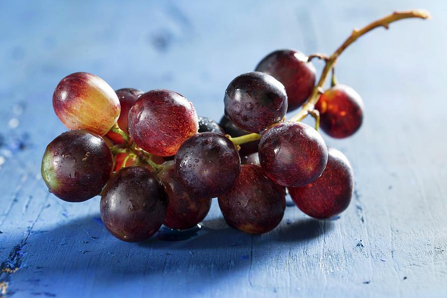 Red Wine Grapes On A Blue Wooden Tabletop Photograph by Mandy Reschke