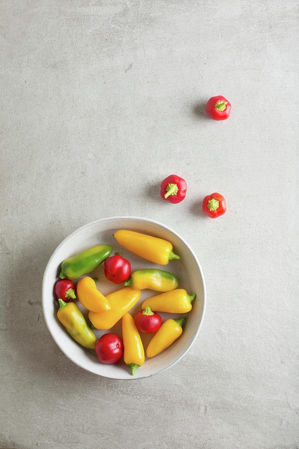 Red, Yellow And Green Mini Peppers In A Bowl And Next To It Photograph by Rose Hewartson