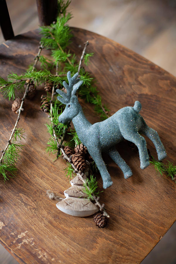 Reindeer Figurine And Larch Twigs On Wooden Chair Photograph by Alicja Koll